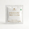 A single packet of Darjeeling First Flush black tea by The Kettlery, presented in a clean white resealable pouch with gold foil lettering on a seamless white background.